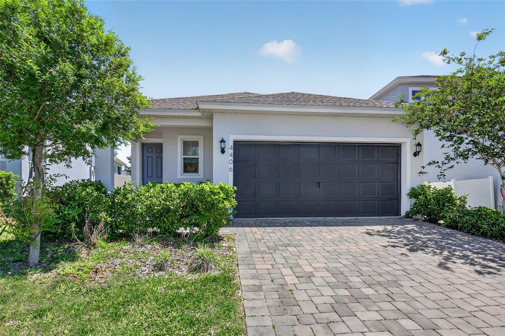 A single-story house with a gray garage door, a paved driveway, and green landscaping — 4406 DAVOS DRIVE, CLERMONT, FL
