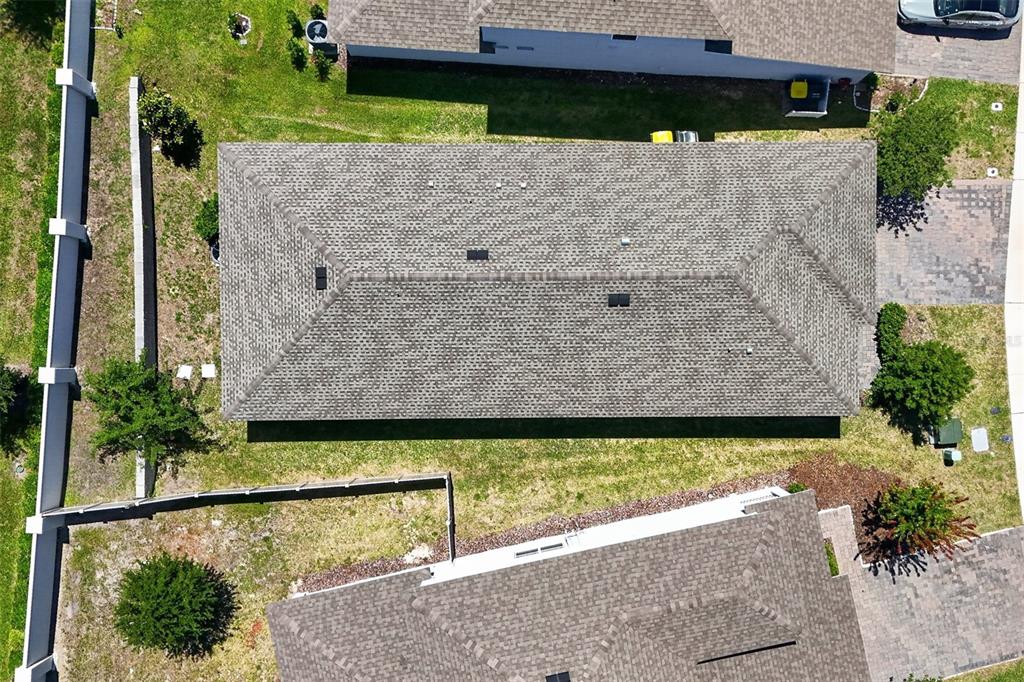An aerial view shows the shingled roof of a rectangular house surrounded by a yard — 4406 DAVOS DRIVE, CLERMONT, FL