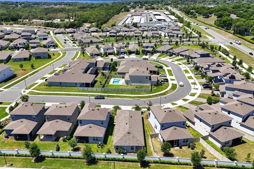 Aerial view of a suburban neighborhood featuring single-family homes, a community pool, and paved streets — 4406 DAVOS DRIVE, CLERMONT, FL