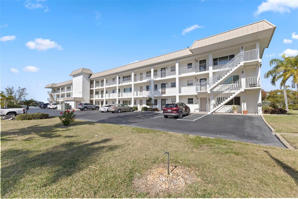 A three-story apartment building with exterior staircases and a parking lot in front — 3330 GULF OF MEXICO DRIVE UNIT 104D, LONGBOAT KEY, FL