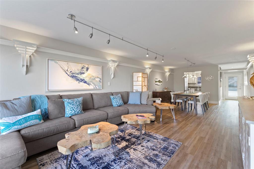 A living room features a gray sectional sofa, live-edge coffee tables, and a blue rug — 3330 GULF OF MEXICO DRIVE UNIT 104D, LONGBOAT KEY, FL