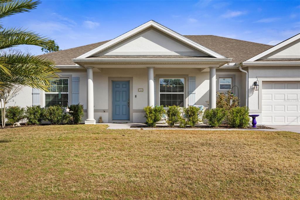 A single-story house with a blue front door, white columns, and a two-car garage — 106 BIRCHWOOD DRIVE, PALM COAST, FL