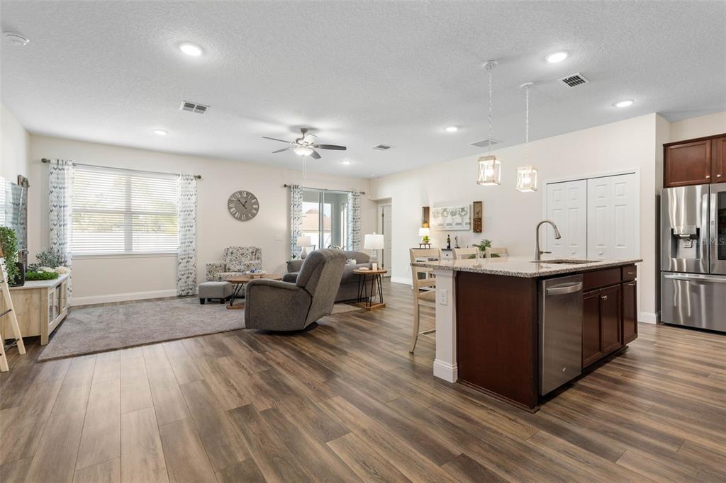 An open-concept living room and kitchen featuring wood-look flooring, a kitchen island, and recessed lighting — 106 BIRCHWOOD DRIVE, PALM COAST, FL