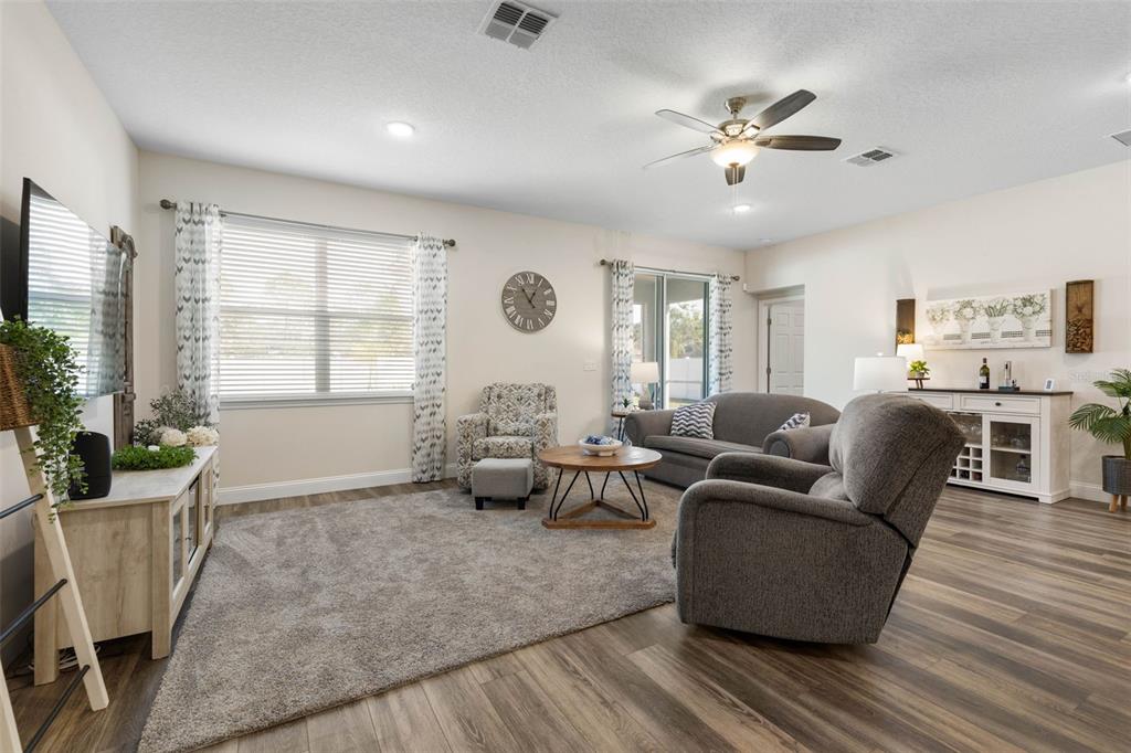 A living room features a gray carpet, a ceiling fan, and a neutral color palette — 106 BIRCHWOOD DRIVE, PALM COAST, FL