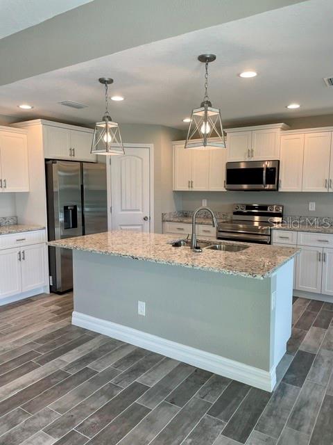 A kitchen features white cabinets, granite countertops, a center island, and wood-look tile flooring — 203 BAYTREE DRIVE, ROTONDA WEST, FL