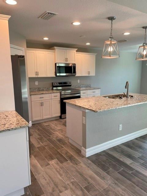 A kitchen features white cabinets, granite countertops, stainless steel appliances, and wood-look tile flooring — 203 BAYTREE DRIVE, ROTONDA WEST, FL