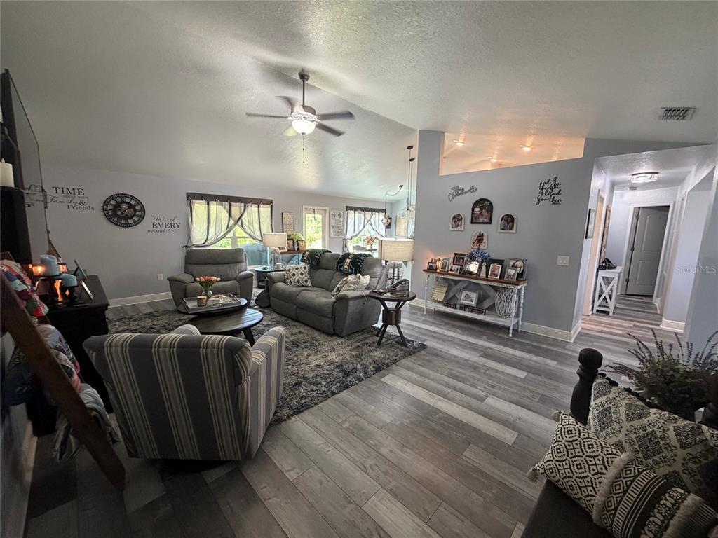 A living room features gray wood-look flooring, a ceiling fan, and a gray sofa set — 1514 HAMLIN STREET, WINTER HAVEN, FL