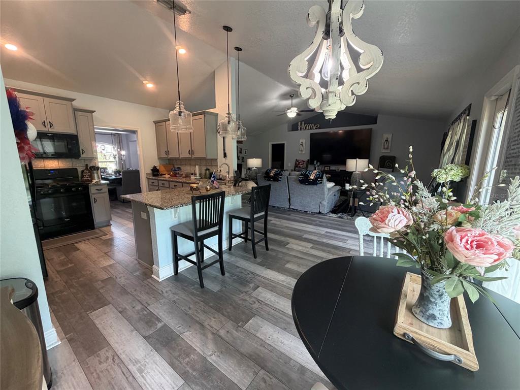 An open-concept kitchen and living area features gray wood-look flooring and a granite-topped island — 1514 HAMLIN STREET, WINTER HAVEN, FL