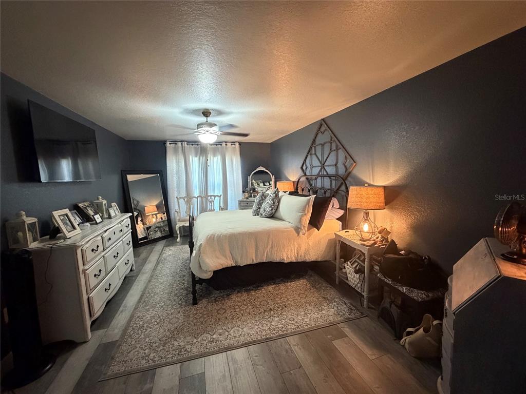 A bedroom features dark walls, a metal bed frame, a white dresser, and wood flooring — 1514 HAMLIN STREET, WINTER HAVEN, FL