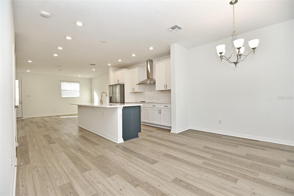 An open-concept kitchen and dining area features white cabinetry, a dark island, and wood flooring — 2948 VOYAGER AVENUE, ST CLOUD, FL