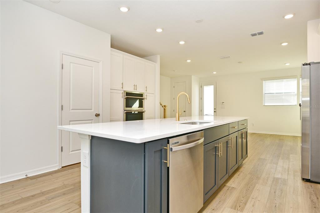 A kitchen features a dark blue island with a stainless steel dishwasher and white cabinets — 2948 VOYAGER AVENUE, ST CLOUD, FL