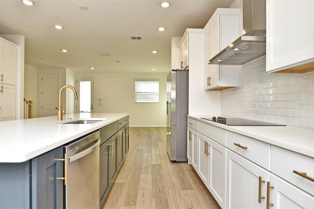 A modern kitchen features white cabinets, a dark blue island, and stainless steel appliances — 2948 VOYAGER AVENUE, ST CLOUD, FL