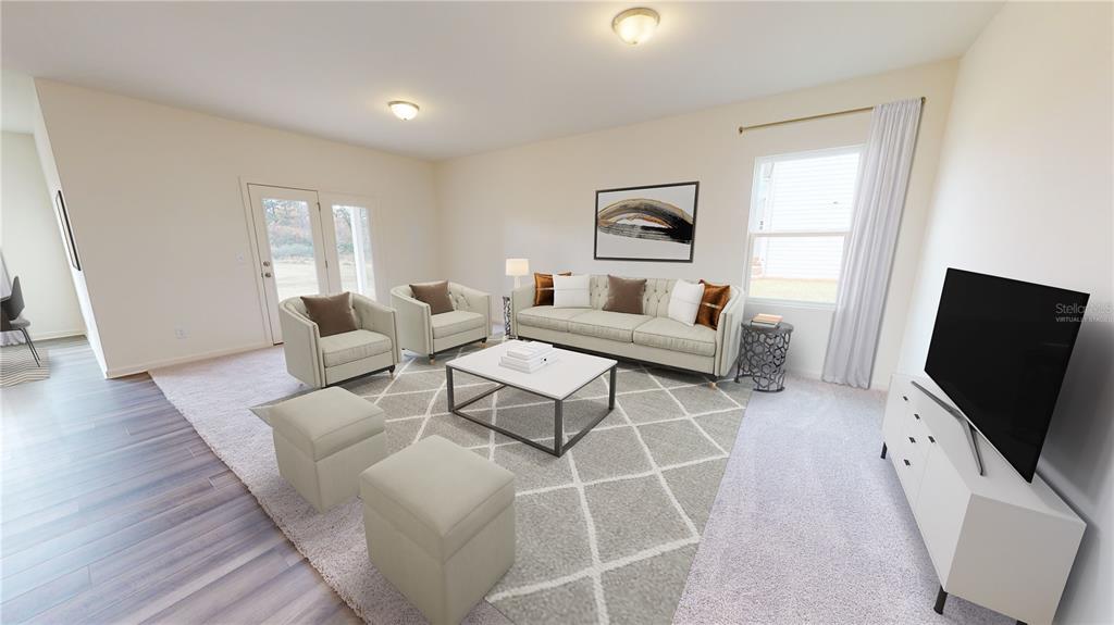 This is a digitally staged living room with a sofa, armchairs, and a television — 5555 BELDI DRIVE, POLK CITY, FL