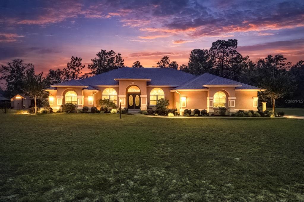 A single-story house with a large lawn and arched windows at sunset — 10411 SW 52ND COURT, OCALA, FL