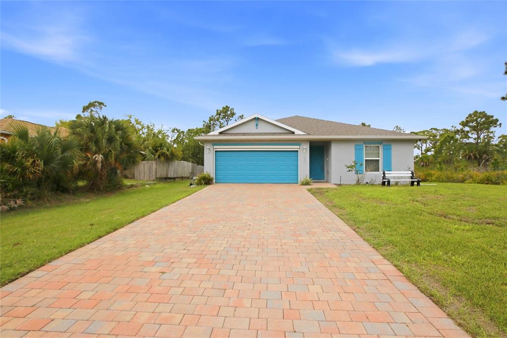 A single-story house with a blue garage door, blue shutters, and a detached storage shed — 3215 SORREL STREET, PORT CHARLOTTE, FL