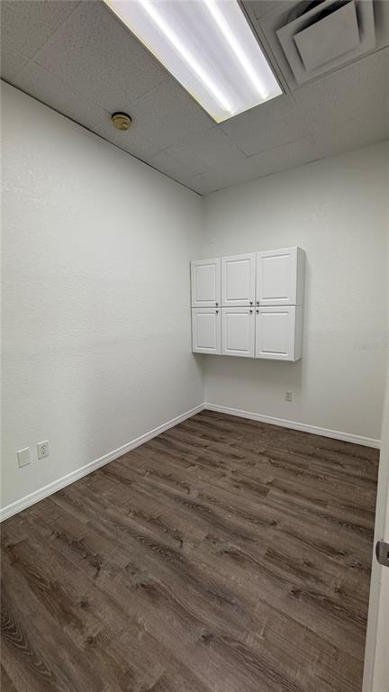 An empty office space features white walls, wood-look flooring, and wall-mounted white storage cabinets — 20101 PEACHLAND BOULEVARD, PORT CHARLOTTE, FL
