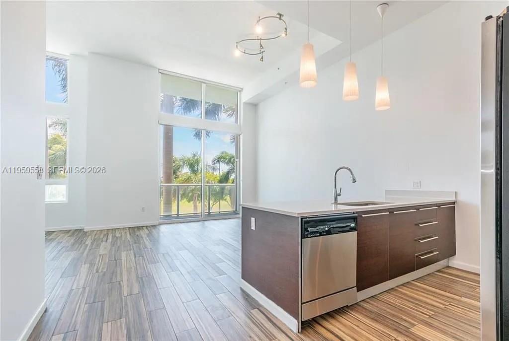 A modern kitchen with dark wood cabinets and stainless steel appliances overlooks a bright living area — 1900 N Bayshore Dr # 506, Miami FL 33132, MIAMI, FL