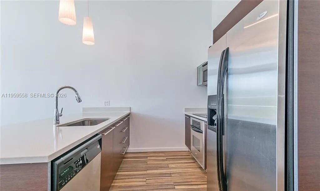 A modern kitchen features stainless steel appliances, dark wood cabinets, and light countertops — 1900 N Bayshore Dr # 506, Miami FL 33132, MIAMI, FL
