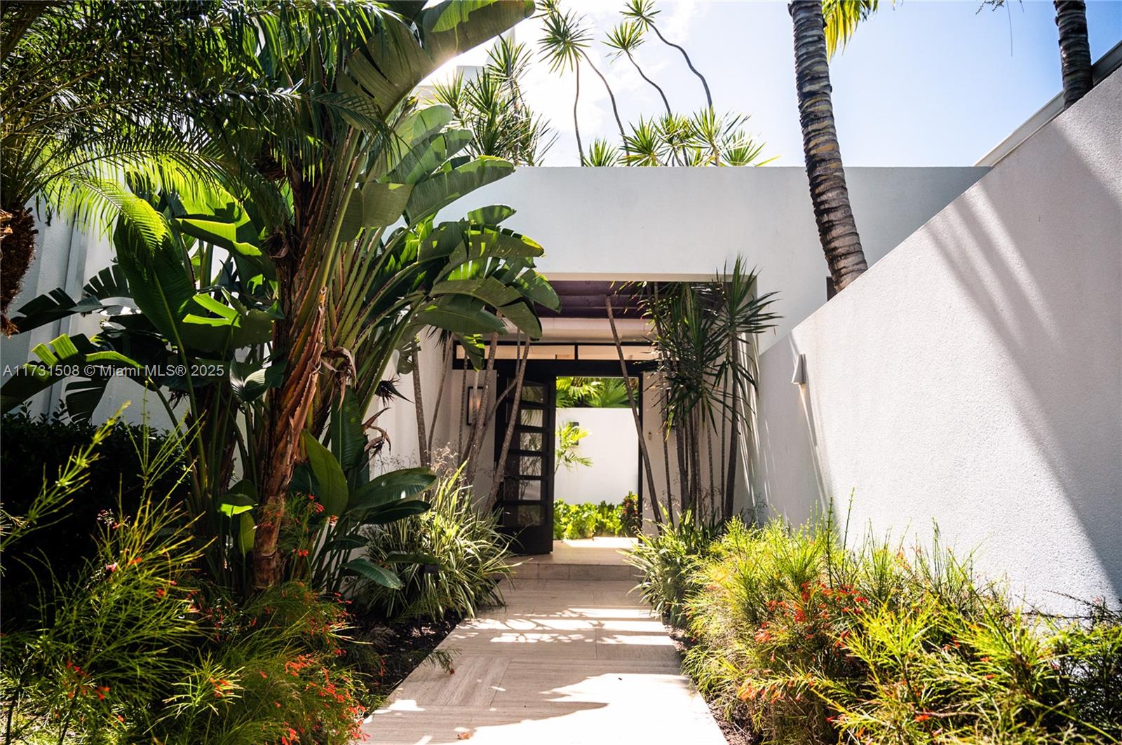 A stone walkway leads through lush tropical landscaping toward a modern white entryway — Villas at Pinney's Beach 2011 # 2011, MN 56467, MN