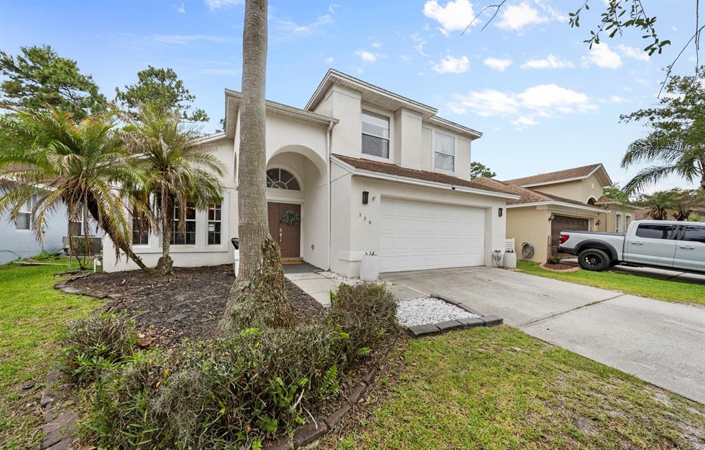 A two-story suburban house with a white stucco exterior, a two-car garage, and palm trees — 526 FITZWILLIAM WAY, ORLANDO, FL