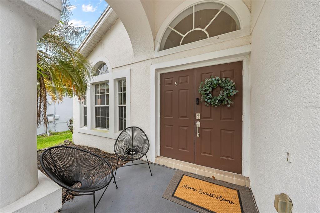 An exterior view of a home entrance with a brown double door and two chairs — 526 FITZWILLIAM WAY, ORLANDO, FL