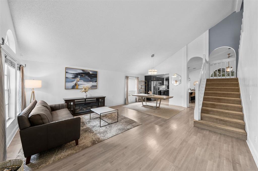 A living room with light wood floors, a brown sofa, and stairs leading to a landing — 526 FITZWILLIAM WAY, ORLANDO, FL