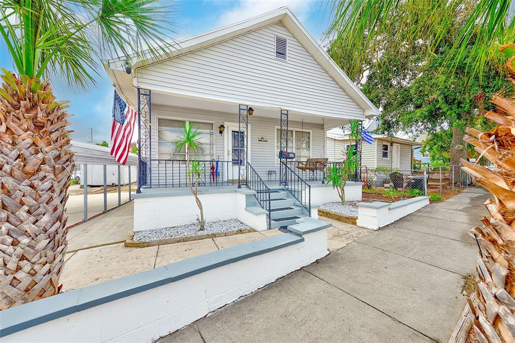 A light gray house with a front porch, metal railings, and a small yard — 632 CROSS STREET, TARPON SPRINGS, FL