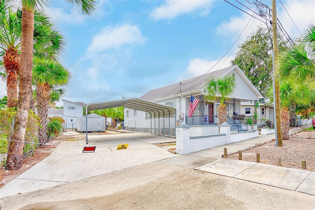 A single-story house with a metal carport and a front porch featuring an American flag — 632 CROSS STREET, TARPON SPRINGS, FL
