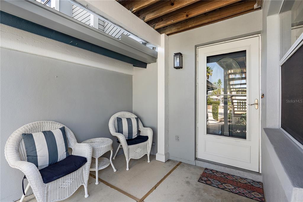 A covered porch features two white wicker chairs, a small table, and a white door — 1374 SIESTA BAYSIDE DRIVE UNIT 1374-D, SARASOTA, FL