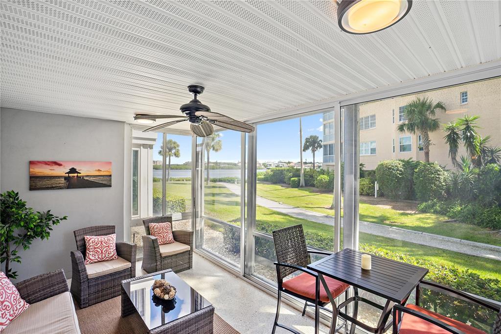 A screened-in porch features wicker furniture, a ceiling fan, and views of a waterfront lawn — 1374 SIESTA BAYSIDE DRIVE UNIT 1374-D, SARASOTA, FL