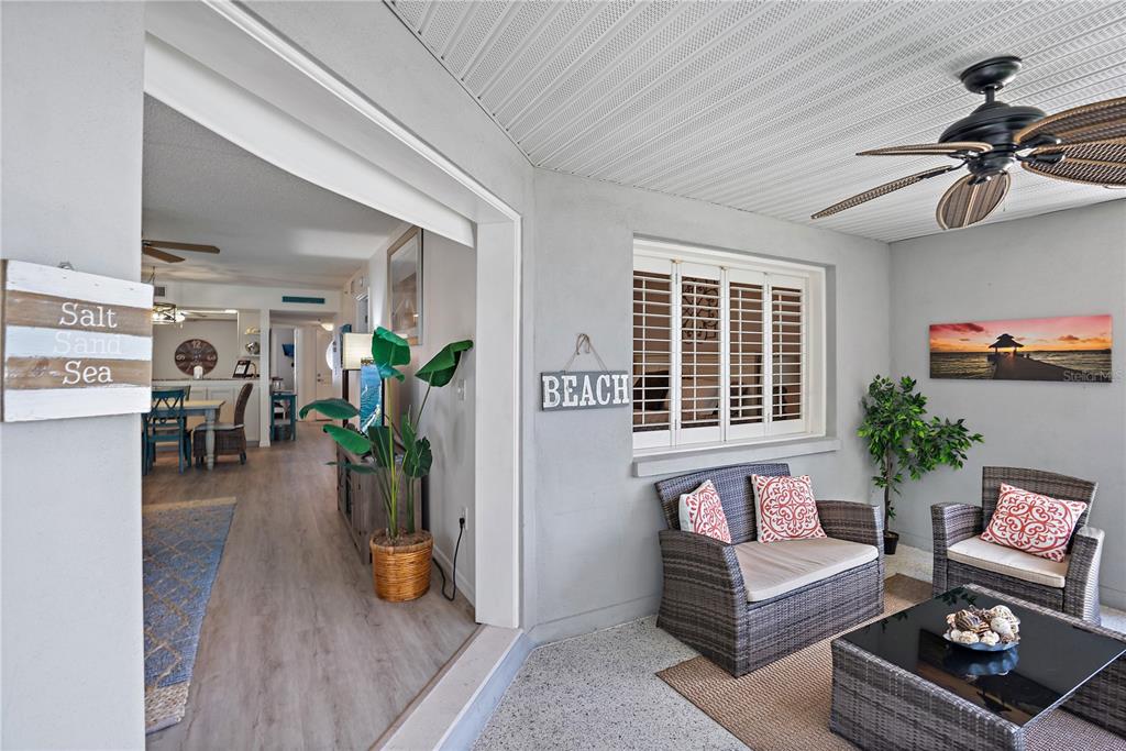 A covered patio with wicker furniture leads into an interior dining and living area — 1374 SIESTA BAYSIDE DRIVE UNIT 1374-D, SARASOTA, FL