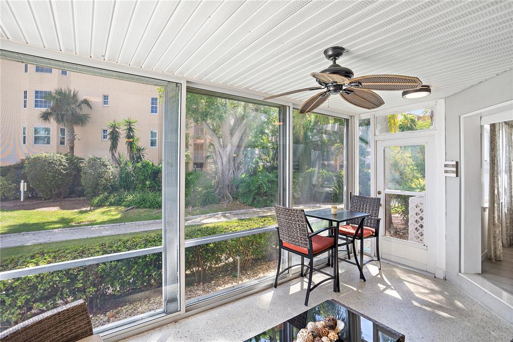 A screened-in porch features a ceiling fan, a small dining set, and views of landscaping — 1374 SIESTA BAYSIDE DRIVE UNIT 1374-D, SARASOTA, FL