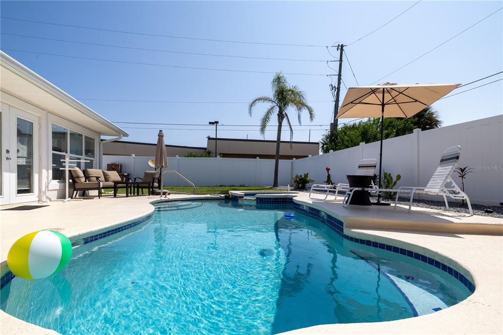 A backyard features a swimming pool with a patio, lounge chairs, and a white fence — 813 E 6TH AVENUE, NEW SMYRNA BEACH, FL
