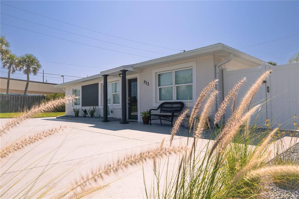 A single-story house with a white exterior, a concrete driveway, and a small front porch — 813 E 6TH AVENUE, NEW SMYRNA BEACH, FL