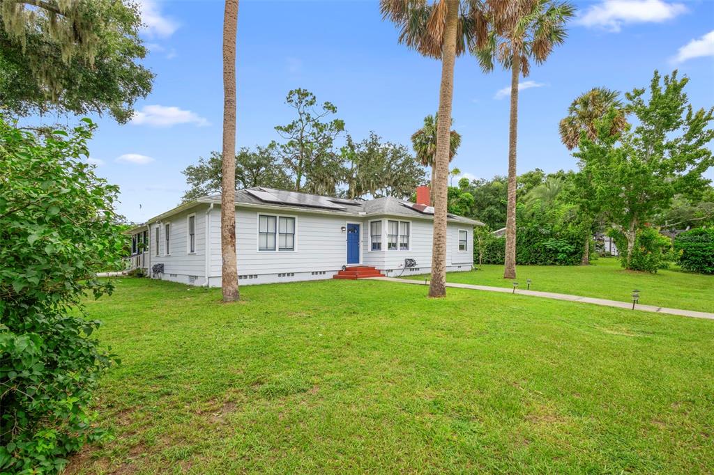 A single-story house with light siding, a blue front door, and solar panels on the roof — 232 W 17TH STREET, SANFORD, FL