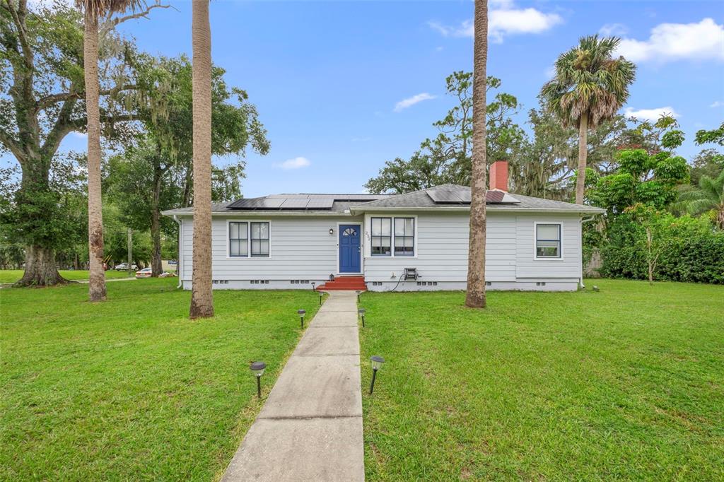 A single-story house with white siding, a blue front door, and solar panels on the roof — 232 W 17TH STREET, SANFORD, FL