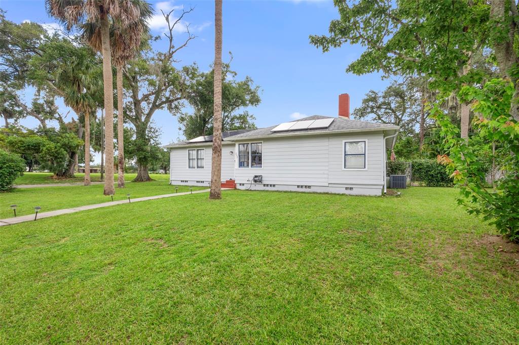 A single-story house with light gray siding, a red chimney, and solar panels on the roof — 232 W 17TH STREET, SANFORD, FL
