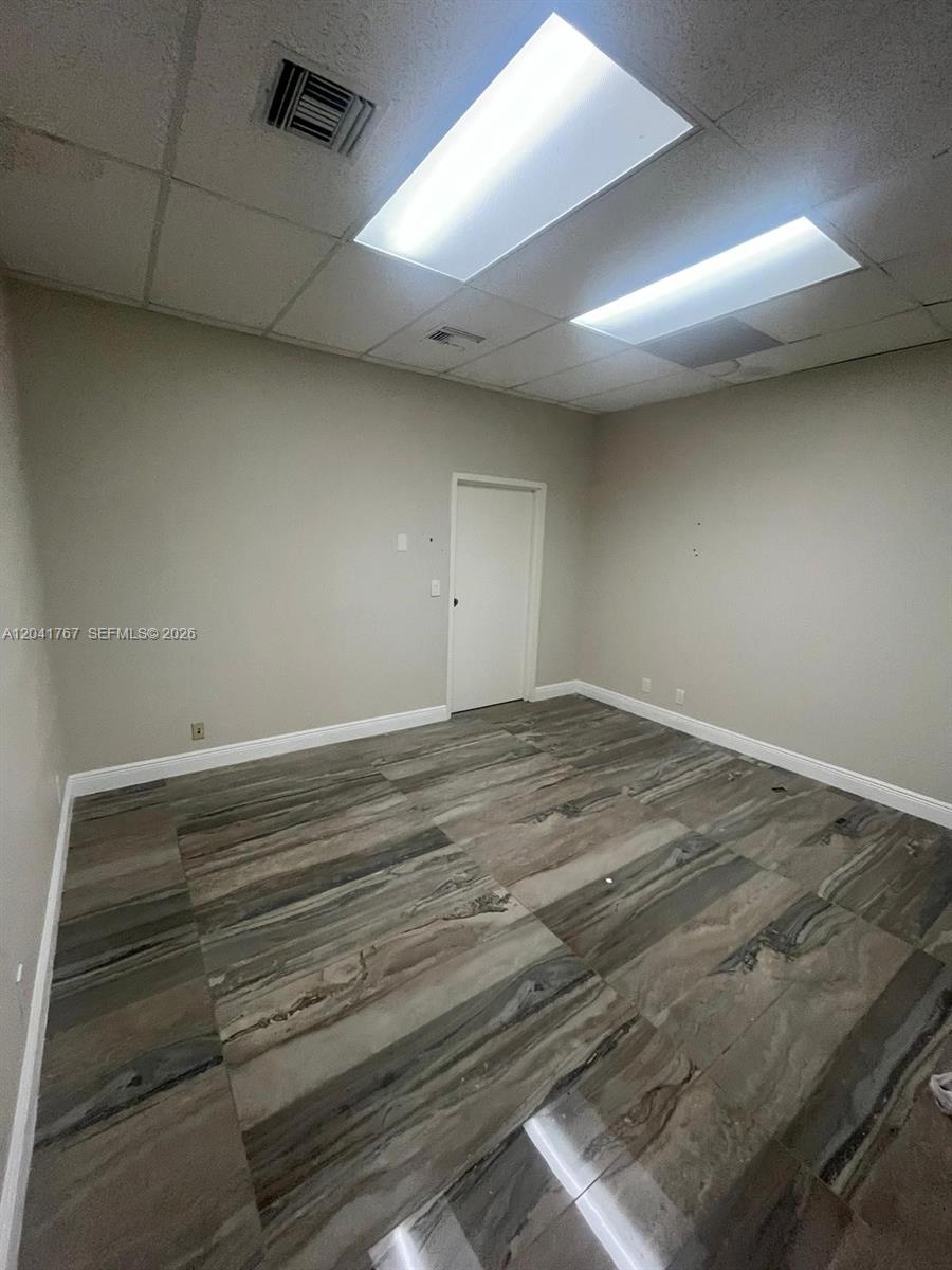 An empty office room features light gray walls, a drop ceiling, and large-format marble-patterned flooring — 6101 W Atlantic Blvd # 205, Margate FL 33063, MARGATE, FL