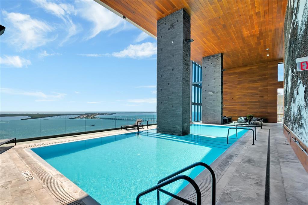 An indoor-outdoor swimming pool features stone pillars, wood-paneled ceilings, and a view of the ocean — 1451 Brickell Avenue # 1202, Miami FL 33131, MIAMI, FL