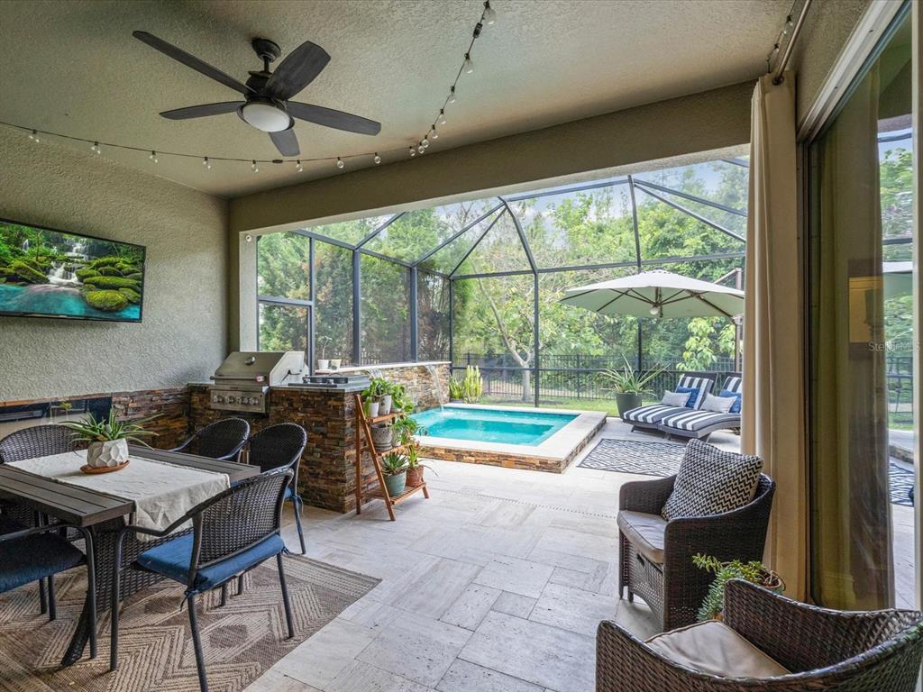 A covered patio features a dining area, outdoor kitchen, and a small pool with a waterfall — 3719 WICKET FIELD ROAD, LUTZ, FL