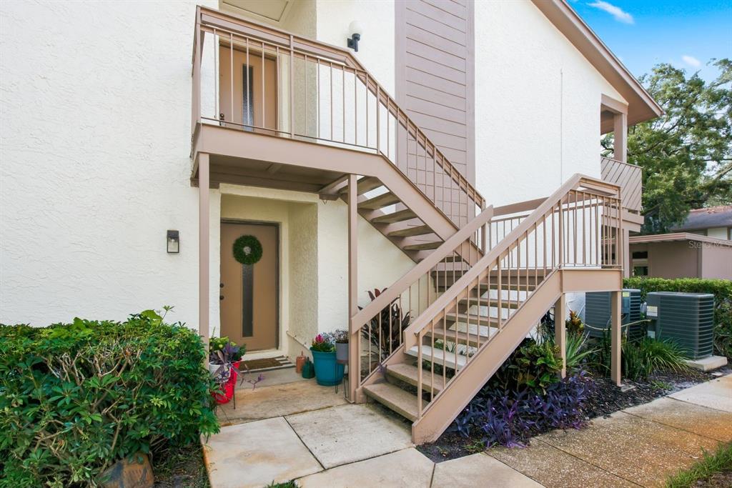 An exterior view of a two-story building with a staircase leading to an upper balcony — 511 MISTLETOE COURT UNIT C, SAFETY HARBOR, FL