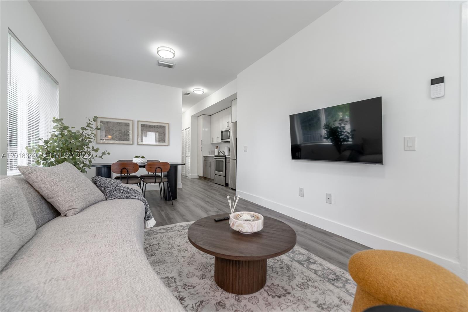 A living room with a wall-mounted television, a round coffee table, and an adjacent kitchen — 44 NW 10th Ave # 2, Miami FL 33128, MIAMI, FL