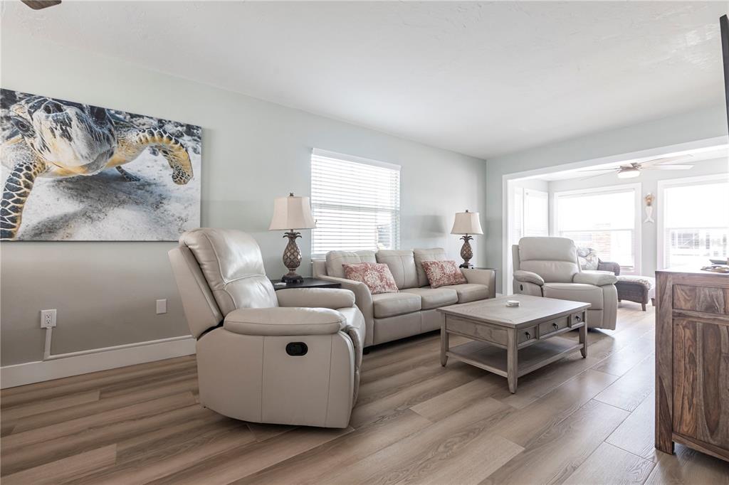 A living room features light-colored furniture, a wooden coffee table, and a sea turtle painting — 6020 MIDNIGHT PASS ROAD UNIT 35, SARASOTA, FL