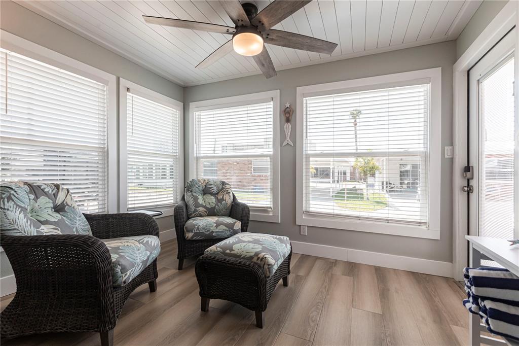 A sunroom features wicker chairs, wood-look flooring, a ceiling fan, and white-trimmed windows — 6020 MIDNIGHT PASS ROAD UNIT 35, SARASOTA, FL