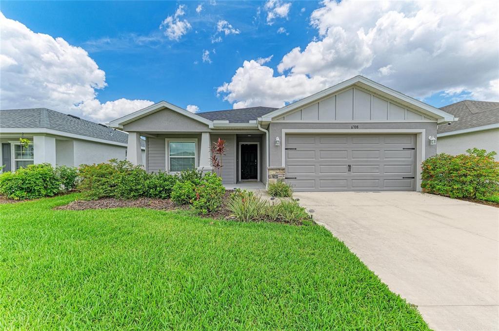 A single-story gray house with a two-car garage and a landscaped front yard — 6708 162ND PLACE E, PARRISH, FL
