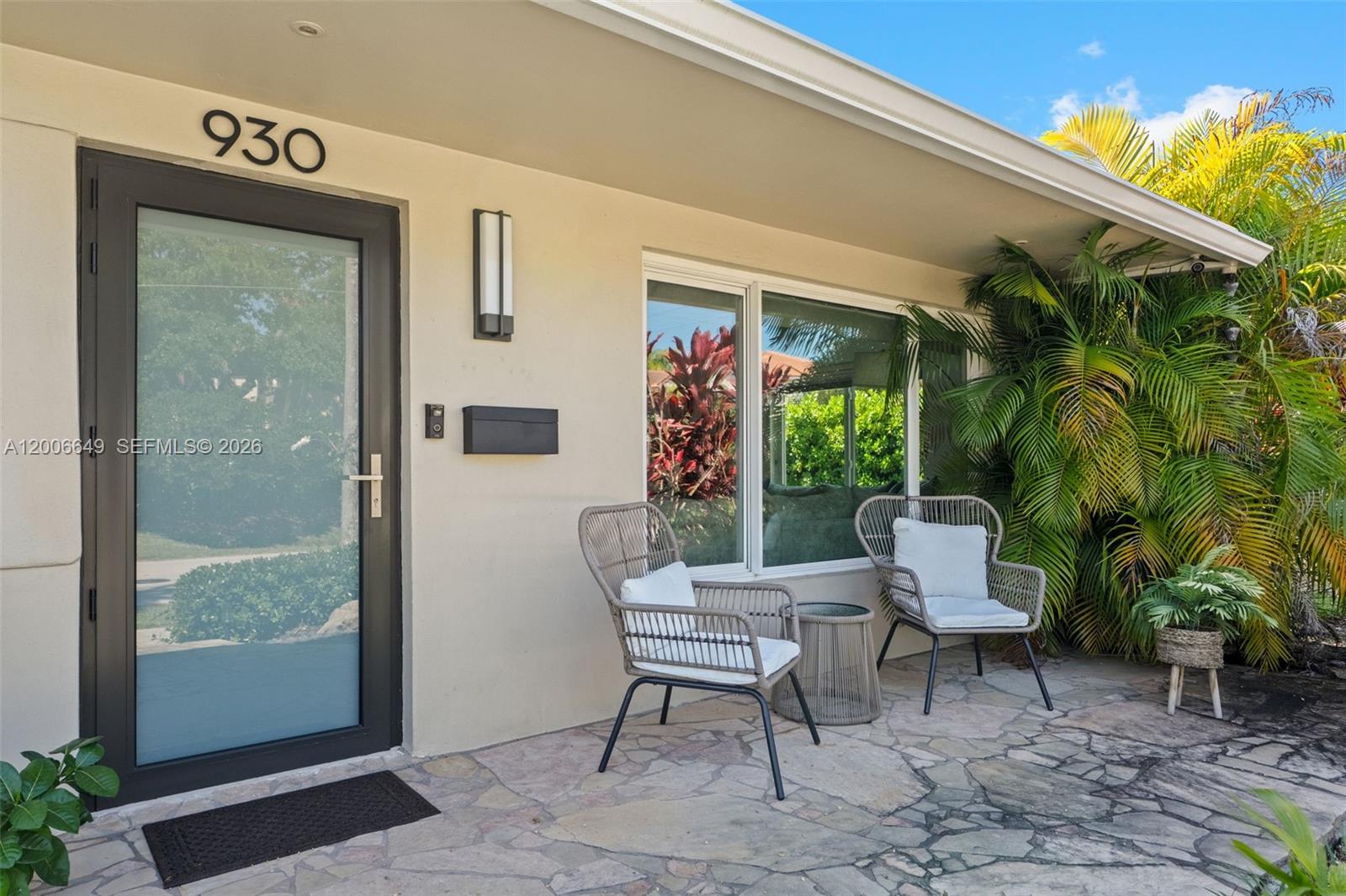 A stone patio features two wicker chairs and a small table outside a front door — 930 N 11th Ct # 0, Hollywood FL 33019, HOLLYWOOD, FL