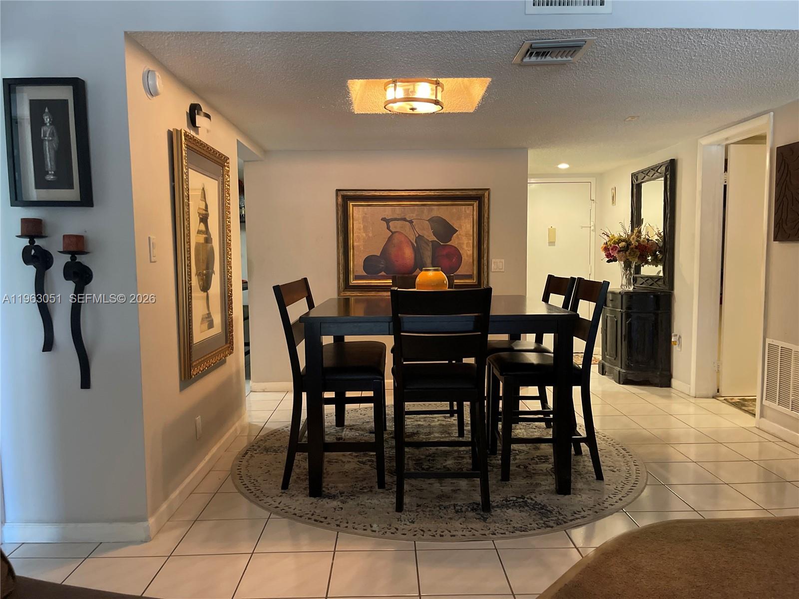 A dining area features a dark wood table with four chairs on a circular rug — 16475 Golf Club Rd # 309, Weston FL 33326, WESTON, FL