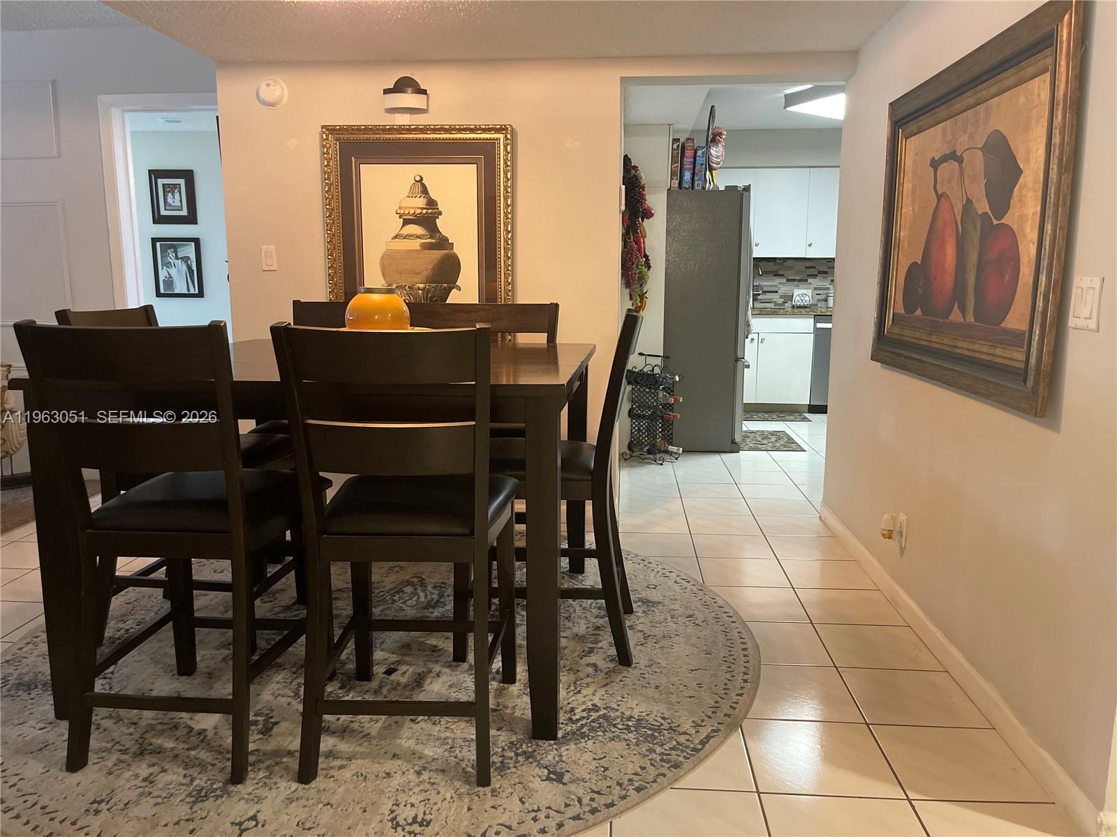 A dining area with a dark wood table and chairs sits on a circular rug — 16475 Golf Club Rd # 309, Weston FL 33326, WESTON, FL