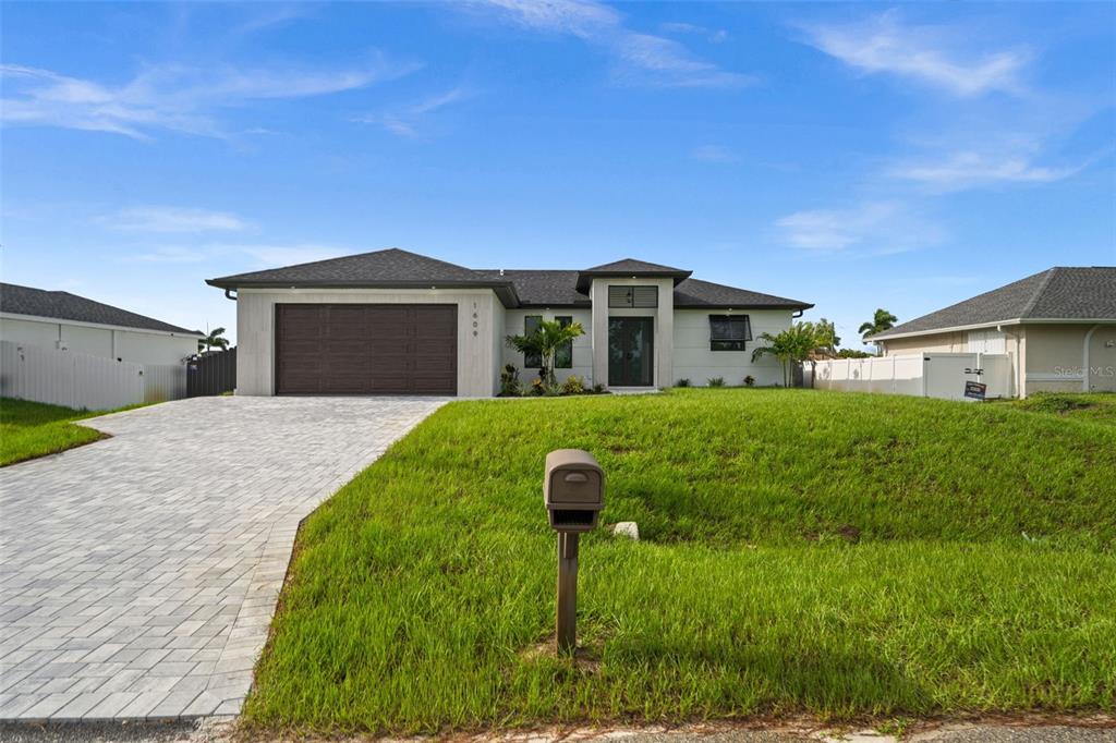 A single-story house with a paved driveway, a two-car garage, and a grassy front yard — 1609 NW 16TH TERRACE, CAPE CORAL, FL