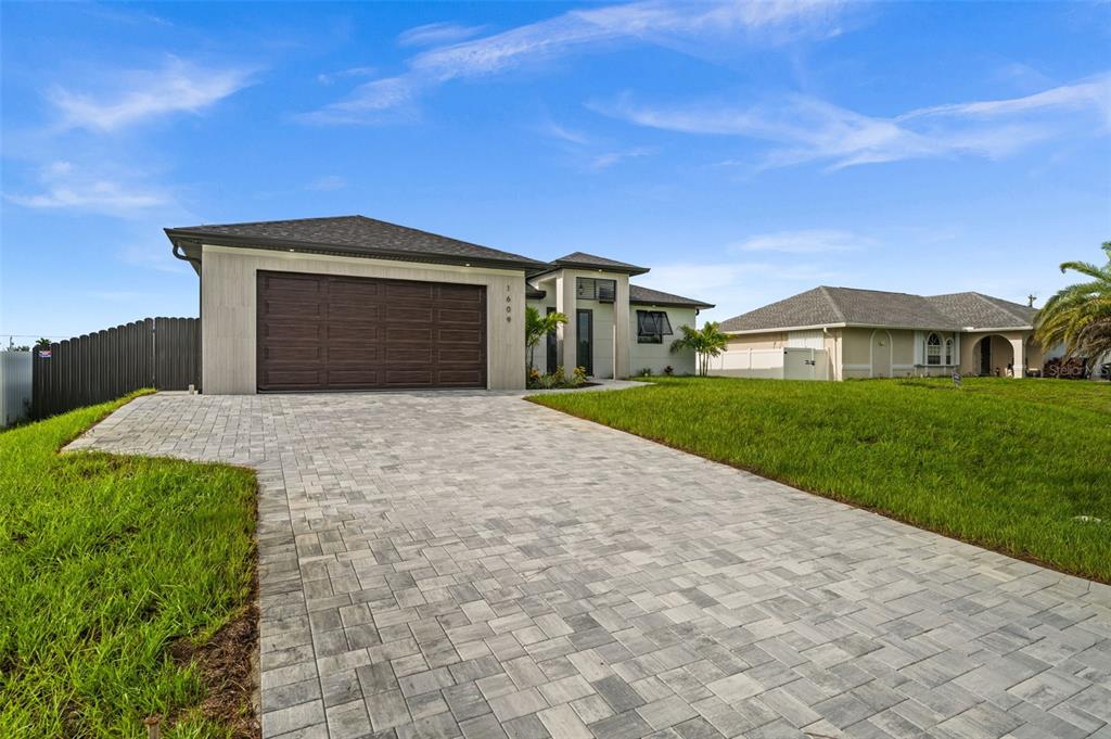 A modern single-story house with a paver driveway and a dark brown garage door — 1609 NW 16TH TERRACE, CAPE CORAL, FL
